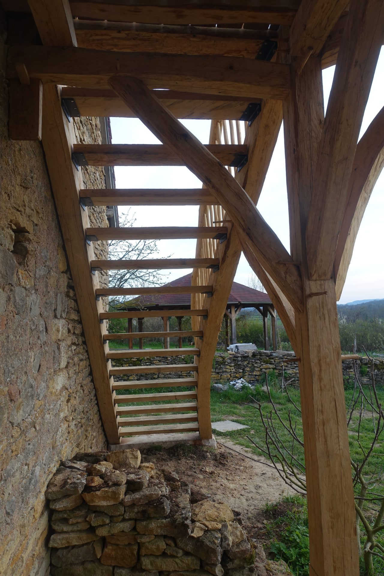 Une terrasse perchée accompagnée de son escalier tout en chêne équarri à la hache